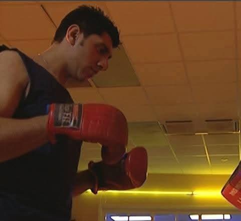 Mak Singh in red boxing gloves during a training scene, 2002