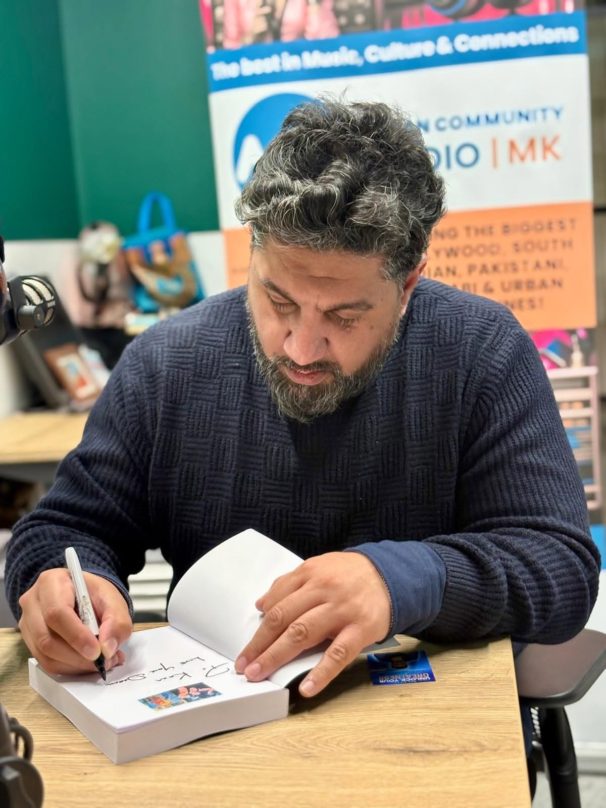 Mak Singh signing a copy of Unlock Your Greatness at the Asian Community Radio MK studio